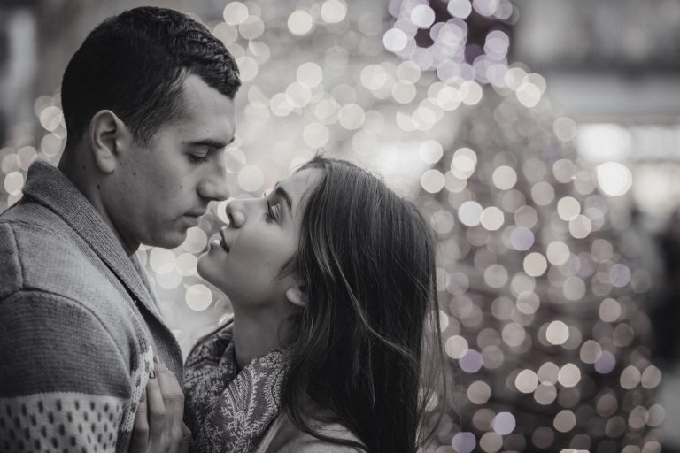 A couple kissing in front of a christmas tree