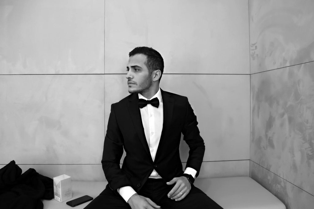 Man in tuxedo sitting elegantly.